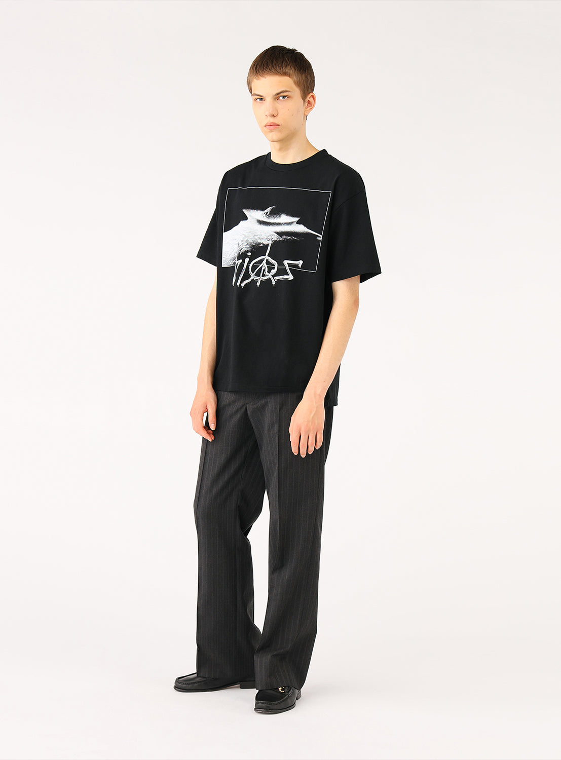 Model in a black t-shirt with a meteor and black pants, full front view, showcasing the casual outfit.