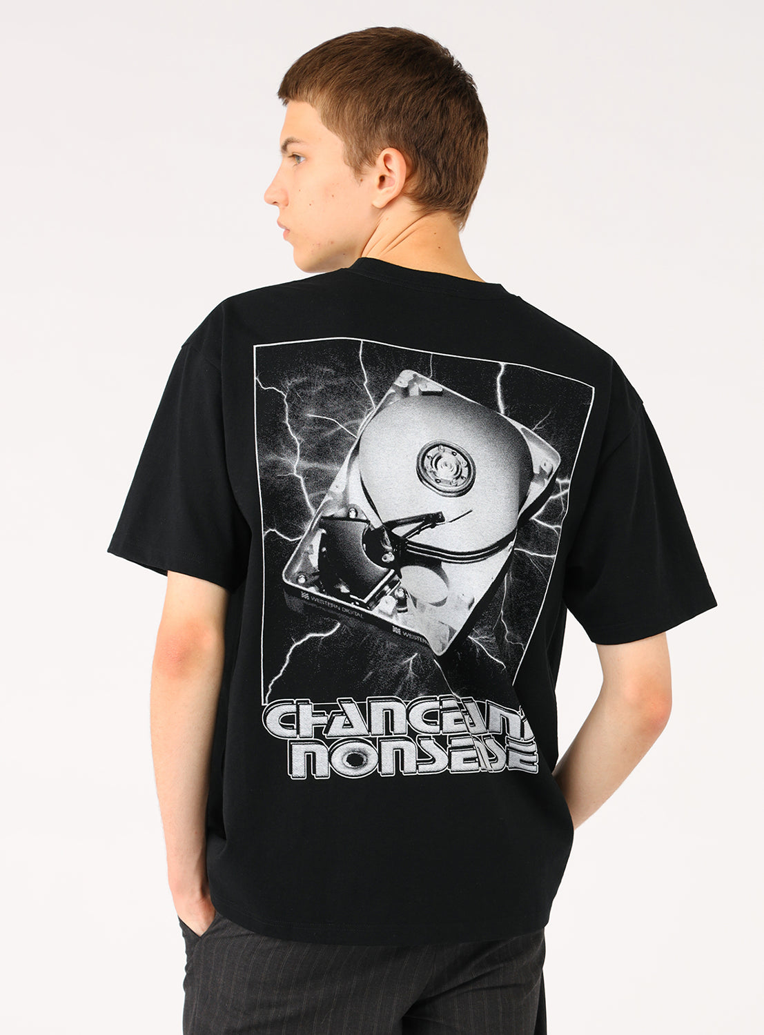 Model wearing a black t-shirt, back view, highlighting the white abstract graphic print and text "CHAOS AND NONSENSE".
