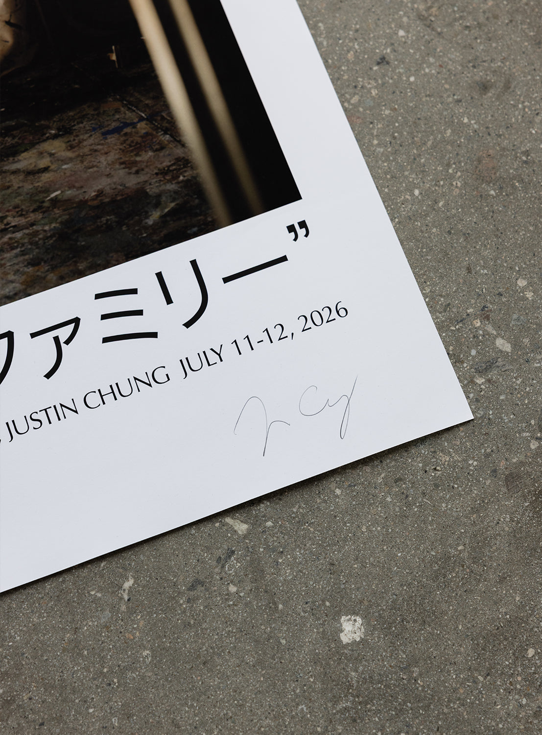 A close-up of a poster corner on a gray floor, featuring Japanese text, JULY 11-12, 2026, JUSTIN CHUNG, and a signature on the white border—showcasing the J. BRIAN x BEAMS POSTER 2 by BEAMS AMERICA as original artwork commemorating the launch of an exclusive model for the brand's 50th-anniversary sneaker.