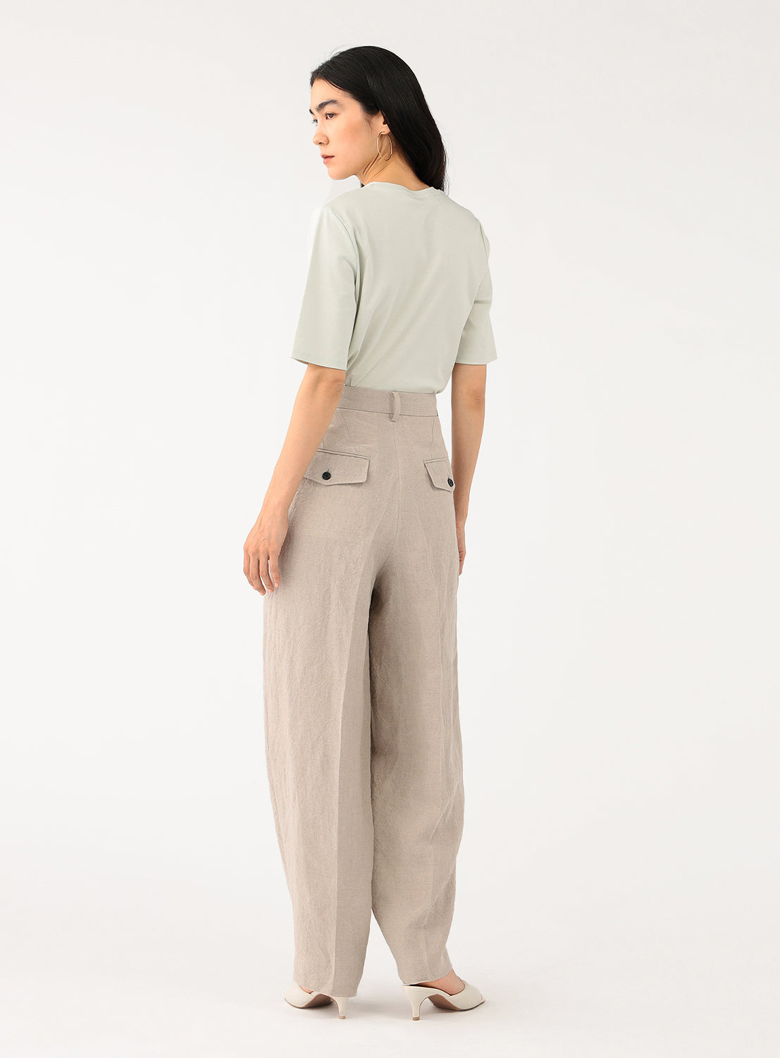 Back view of a model in the off-white pants, highlighting the drape of the fabric and the full leg.