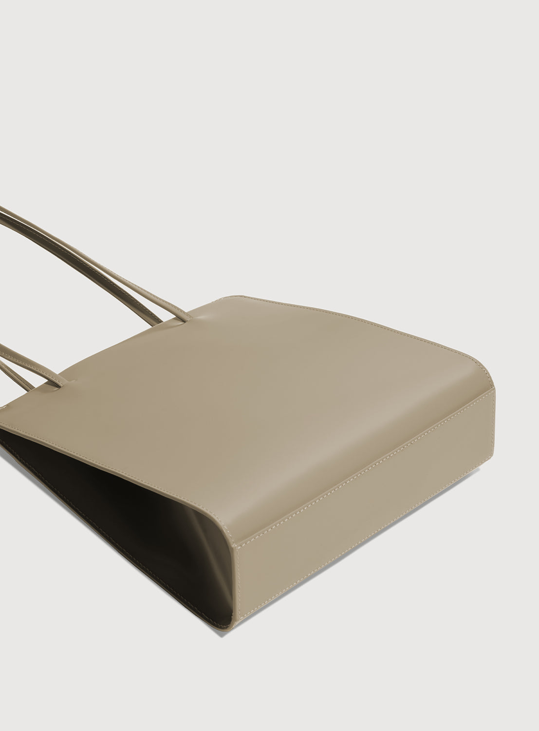 Bottom view of latte brown square handbag with long, ribbon-like straps.