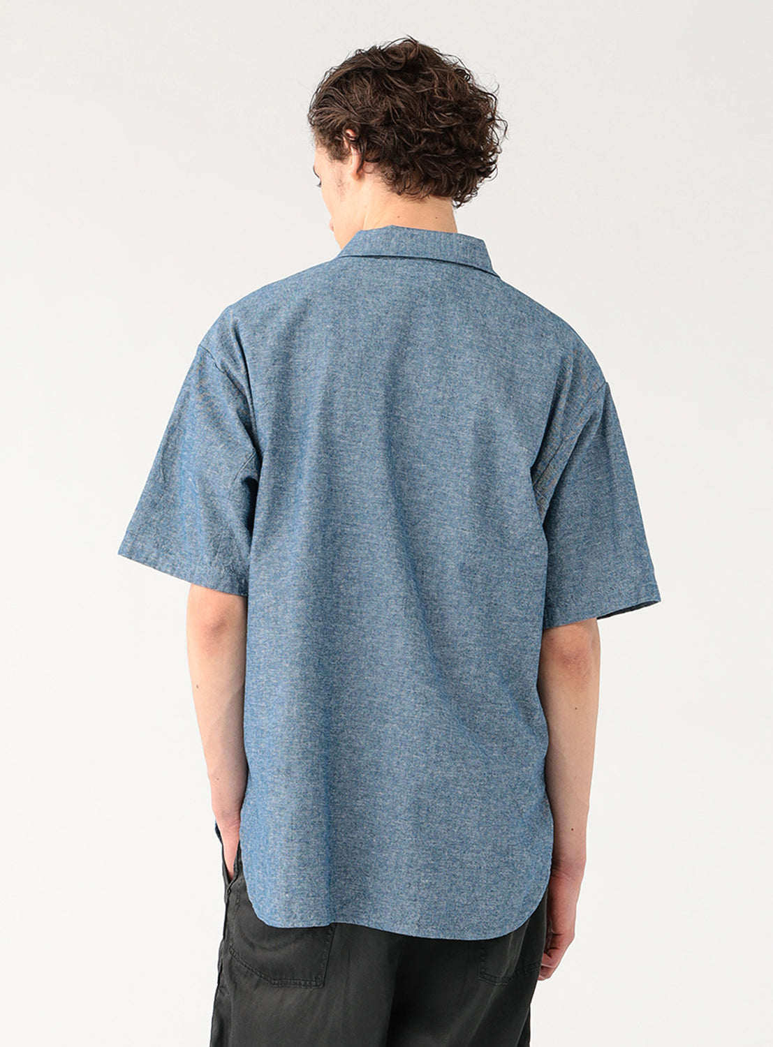 Model wearing a blue military pullover shirt, back view, highlighting the shirt's natural drape and voluminous design.