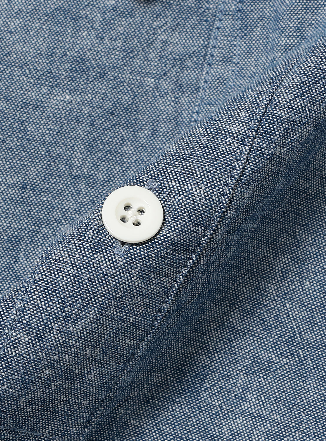 Close-up of blue military pullover shirt fabric and white button, detailing the soft cotton back satin texture.