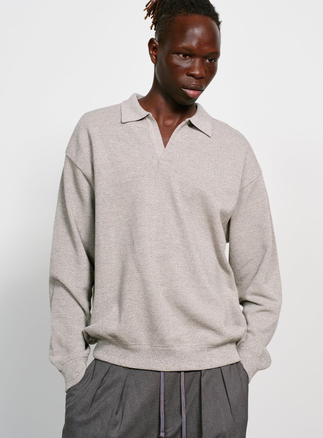 Model wearing a gray sweater with a collar on a white background.
