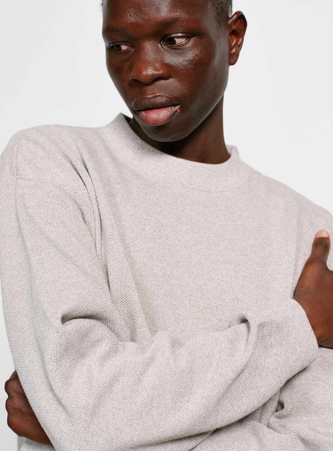Close up of a model wearing a grey crew neck sweater.