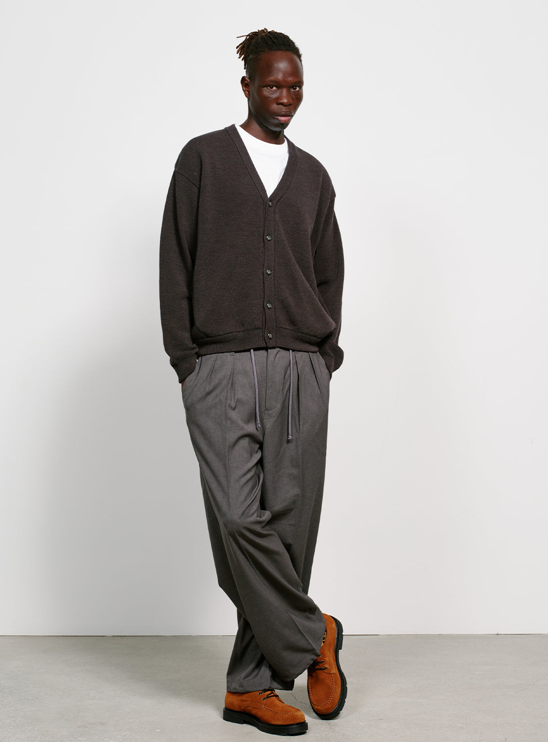 Model wearing a gray button down cardigan with pockets on a white background.