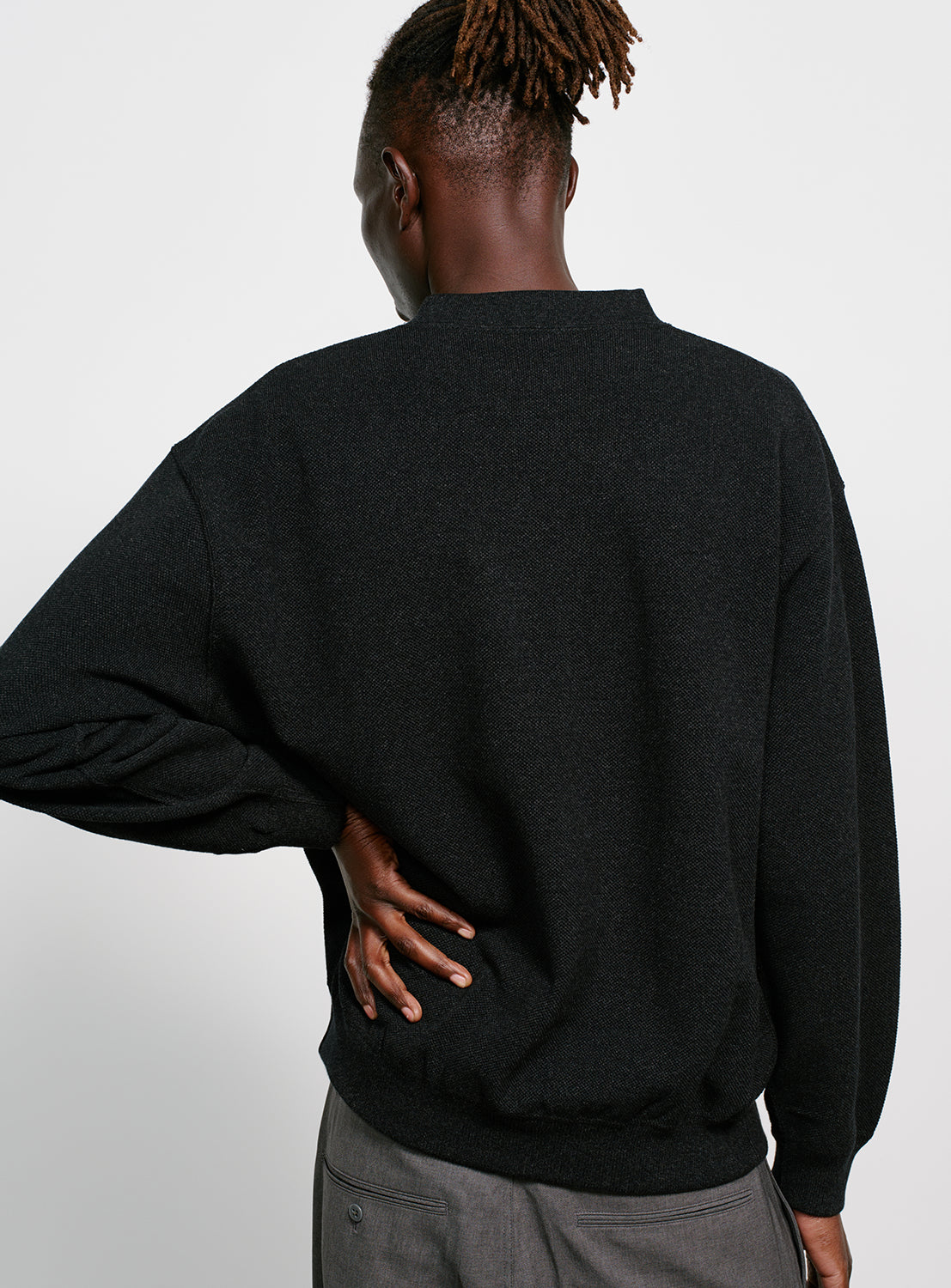 Back of a model wearing a black crew neck sweater.