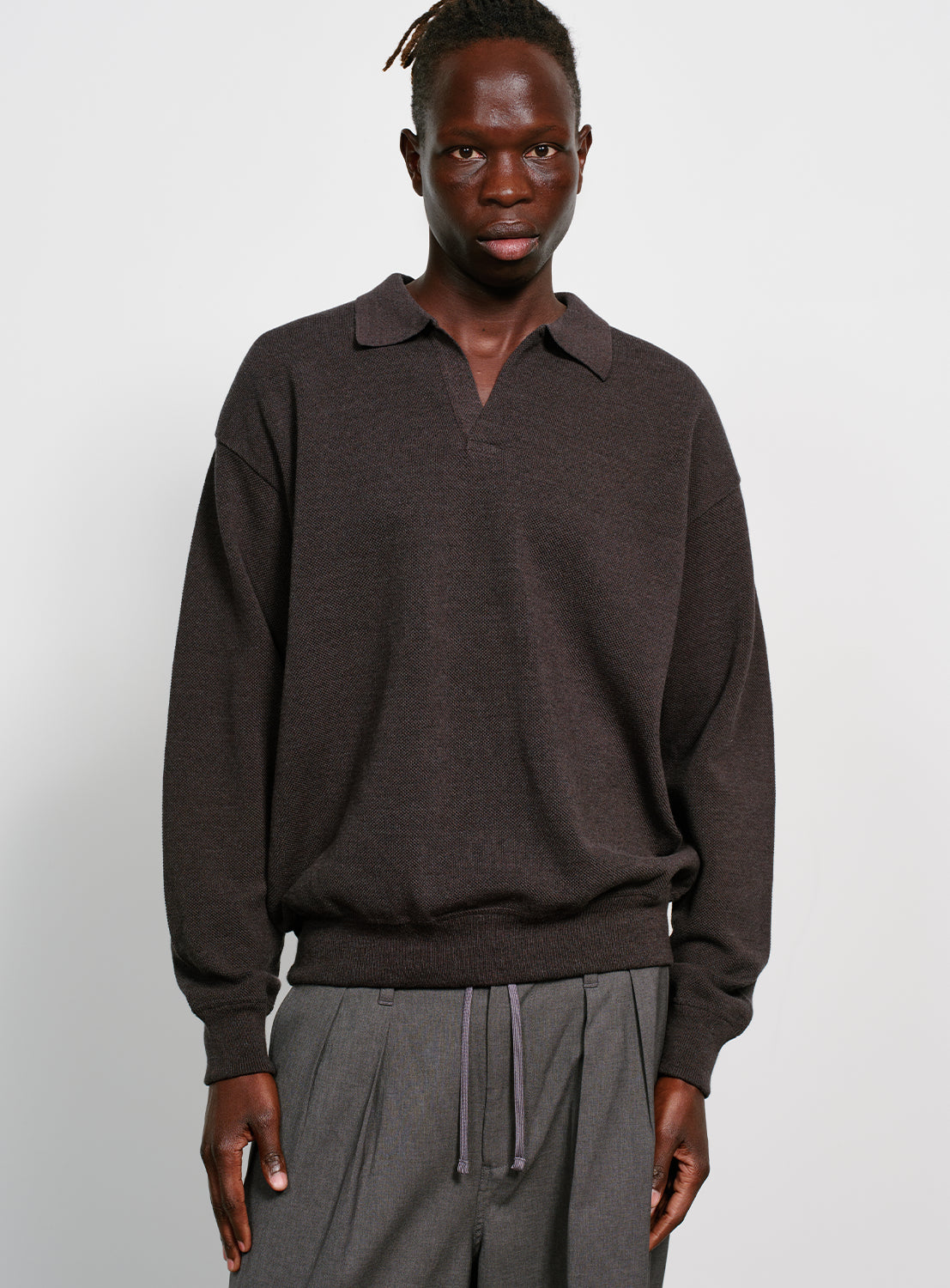 Model wearing a dark gray sweater with a collar on a white background.