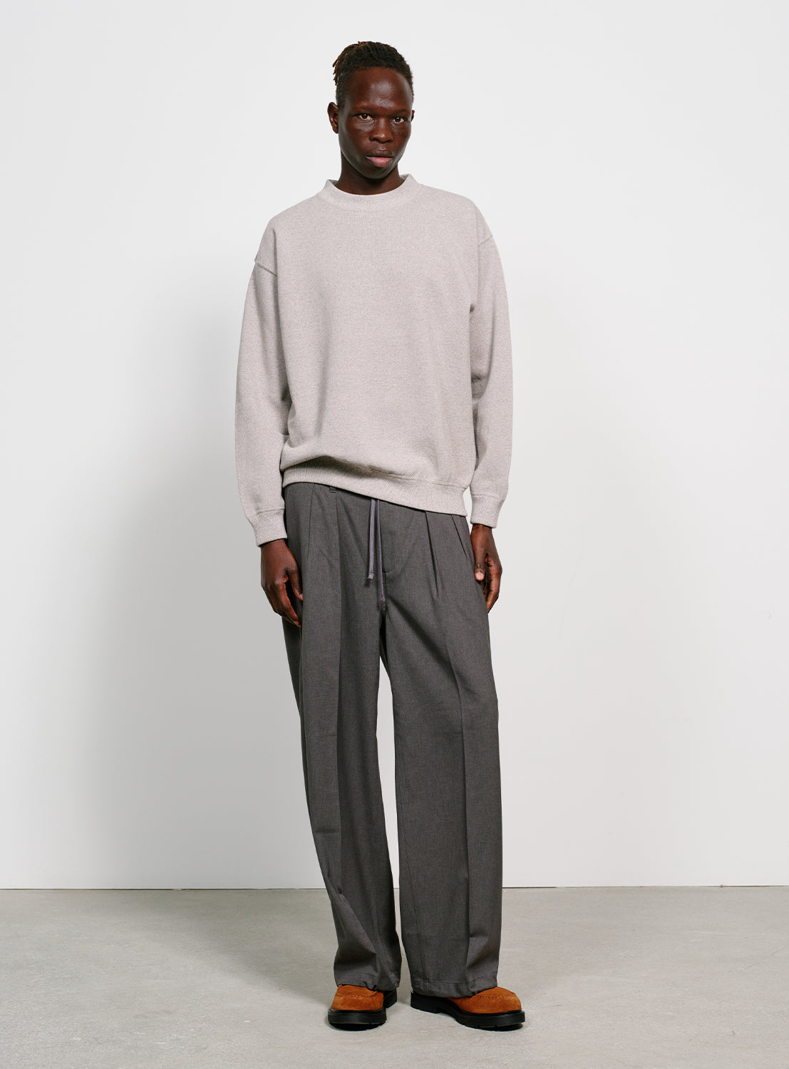 Model wearing a grey crew neck sweater.