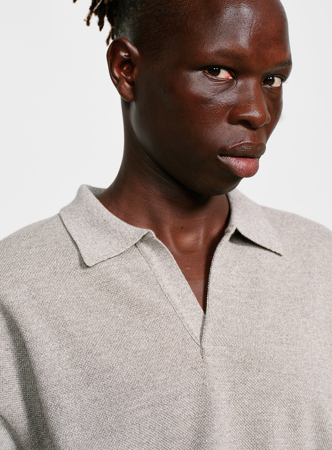 Close up of a model wearing a gray sweater with a collar on a white background.