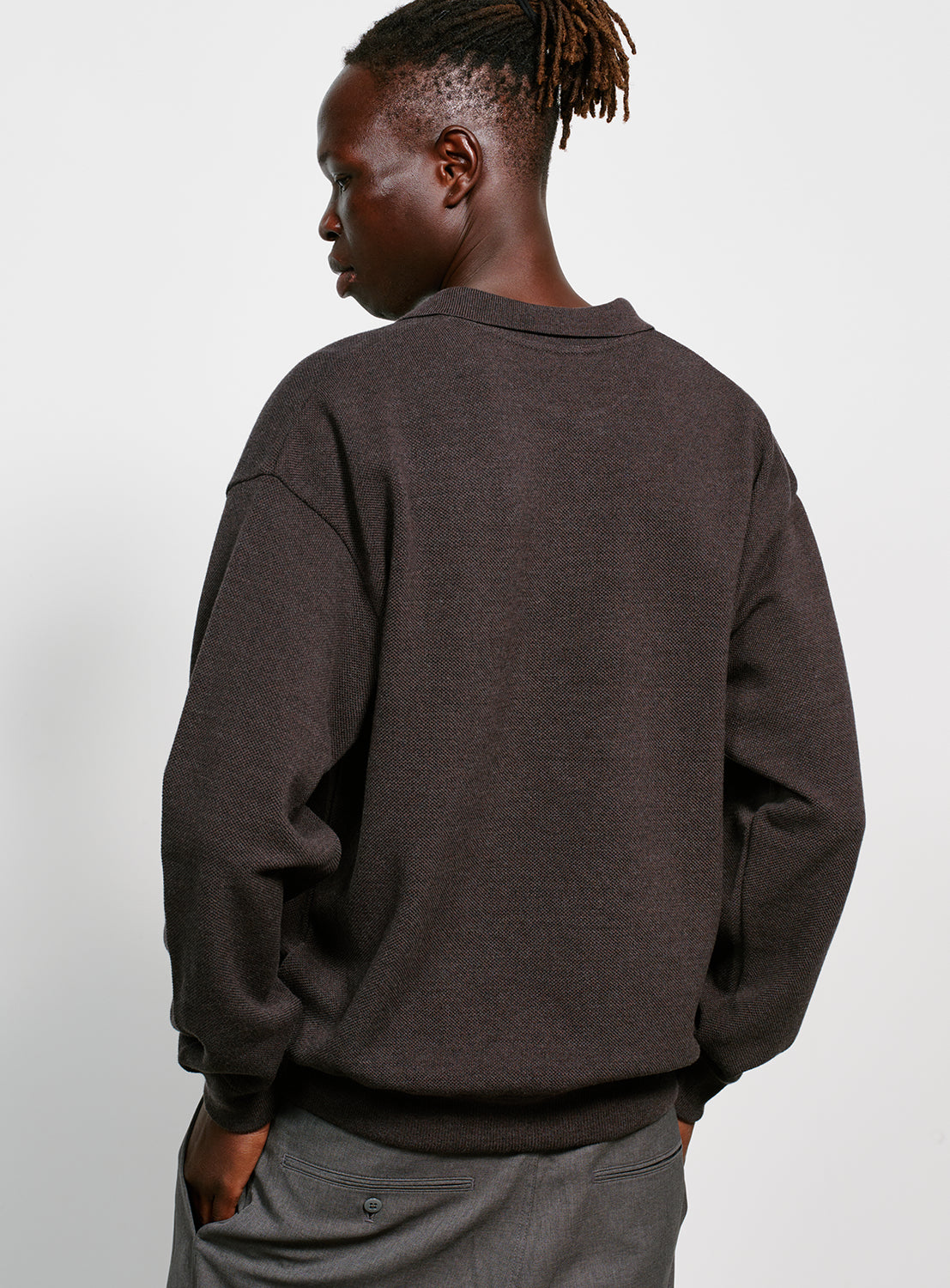 Back of a model wearing a dark gray sweater with a collar on a white background.