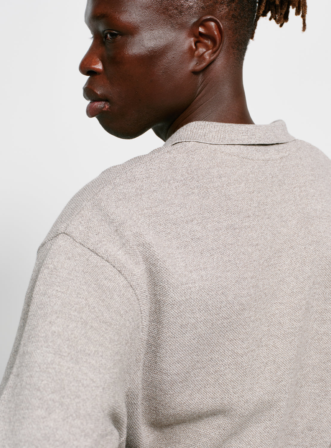 Back of a model wearing a gray sweater with a collar on a white background.