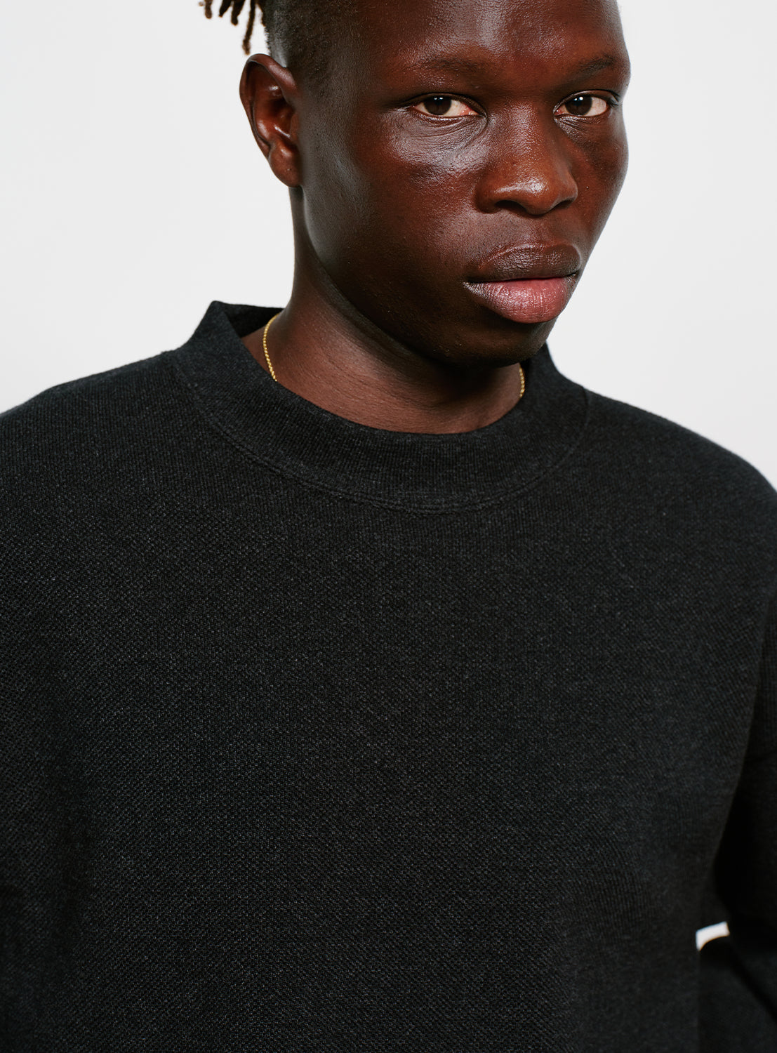 Close up of model wearing a black crew neck sweater.