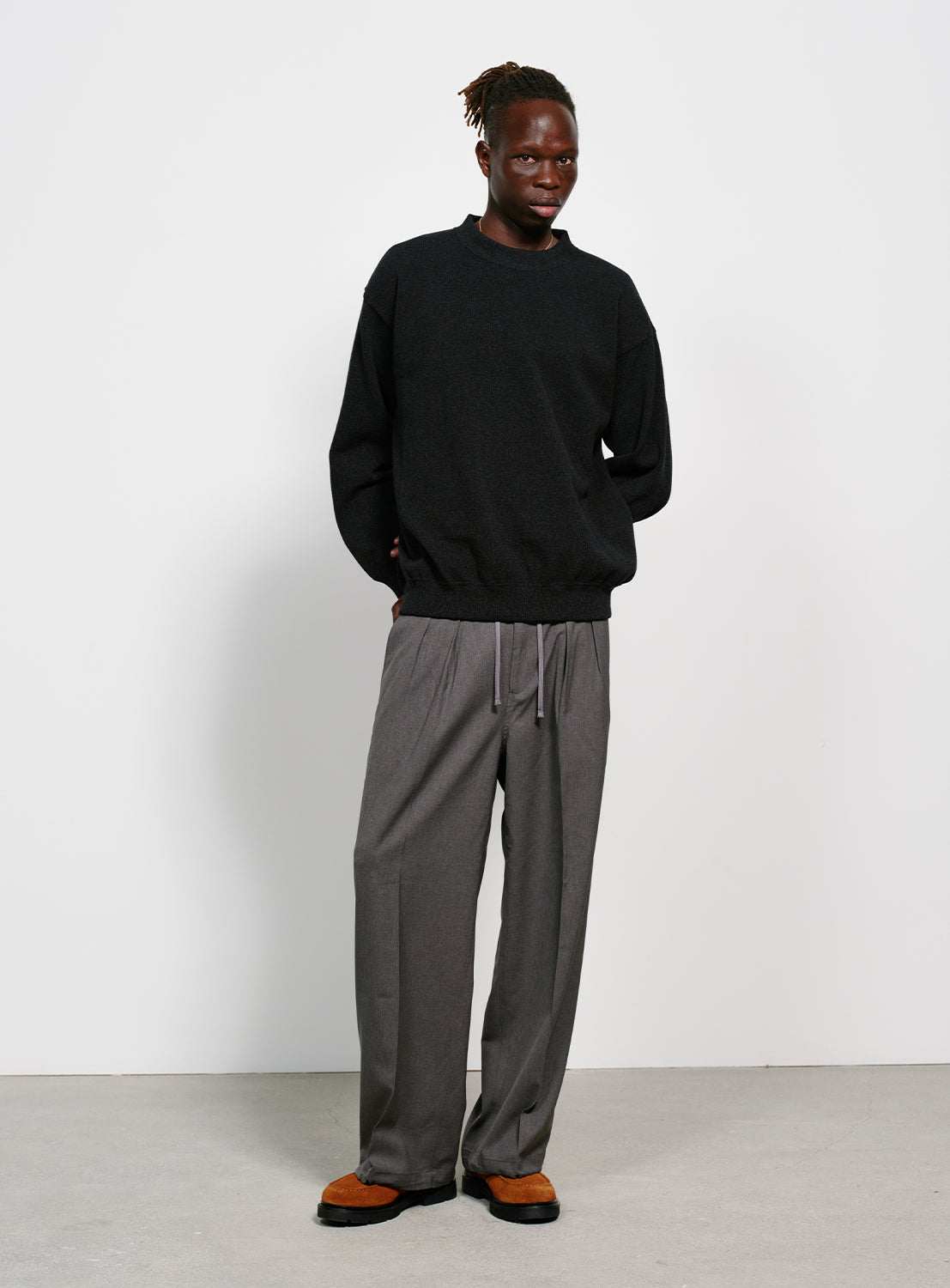 Model wearing a black crew neck sweater.