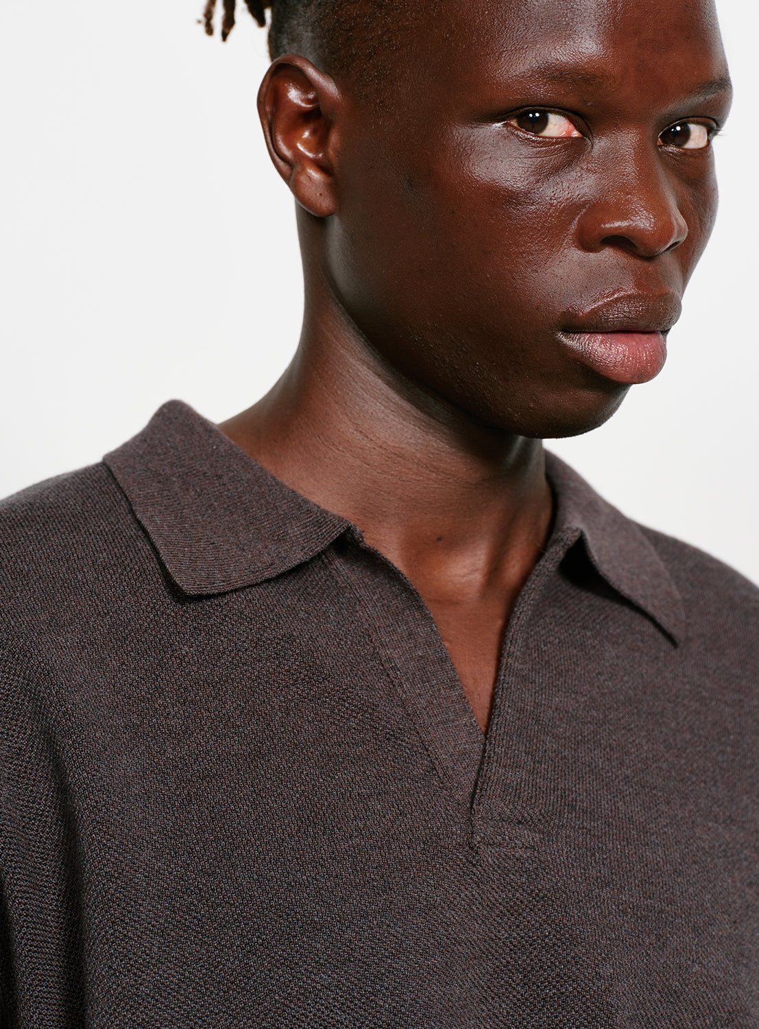 Close up of a model wearing a dark gray sweater with a collar on a white background.