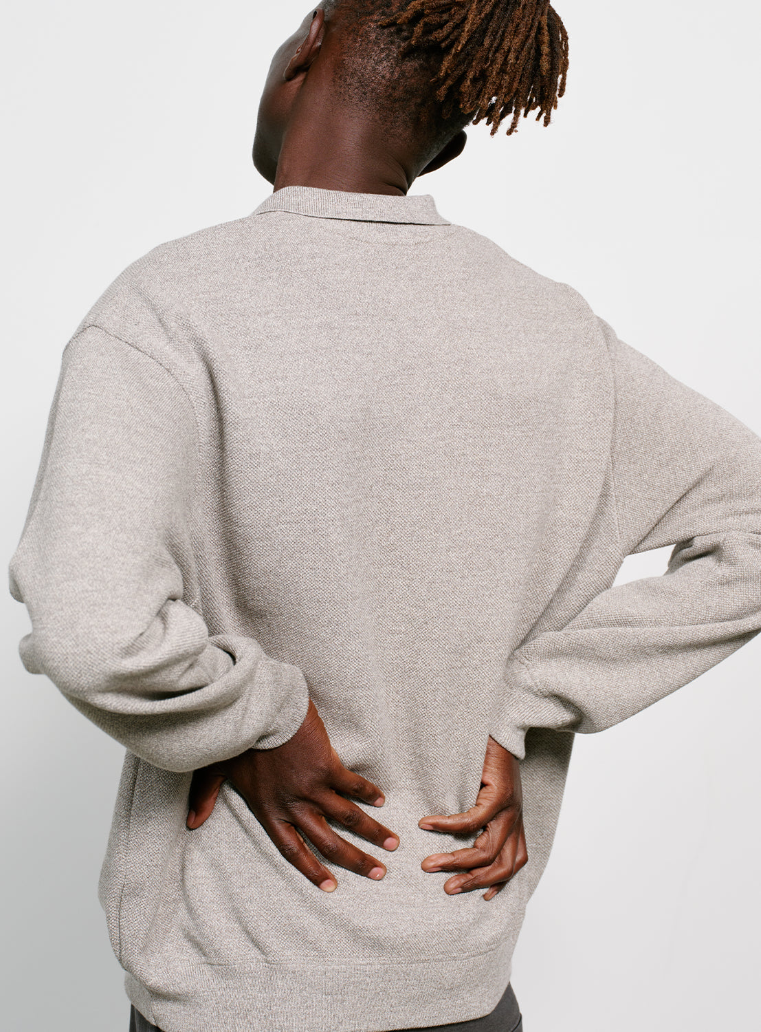 Back of a model wearing a gray sweater with a collar on a white background.