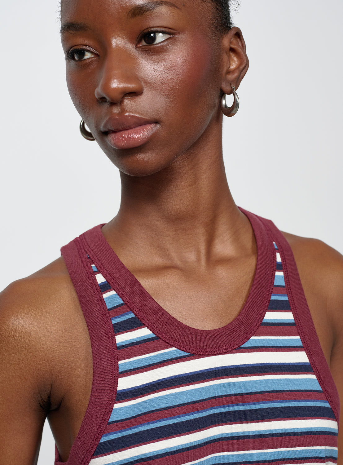 Close up of model wearing a striped tank top with maroon, blue, and white stripes with maroon trim.