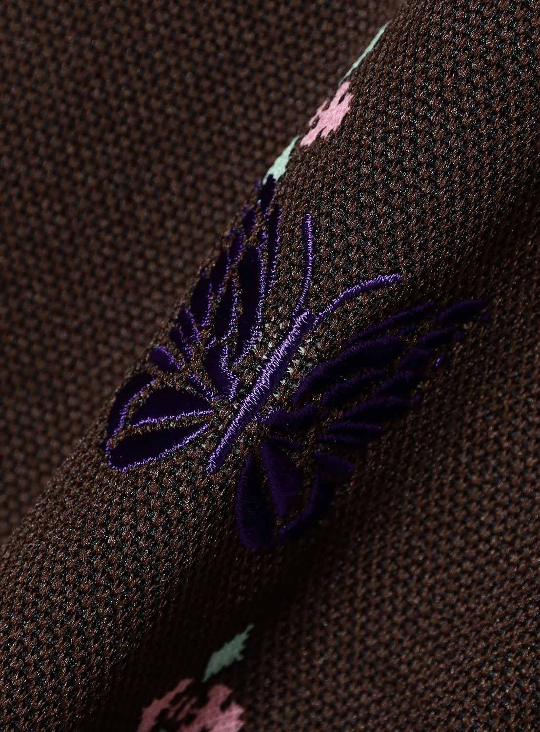 Close-up of a brown textured fabric with embroidered purple butterfly. 