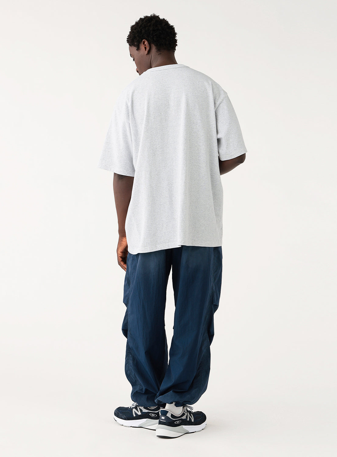 Back view of a man showcasing the fit of an ash grey oversized t-shirt demonstrating drape.