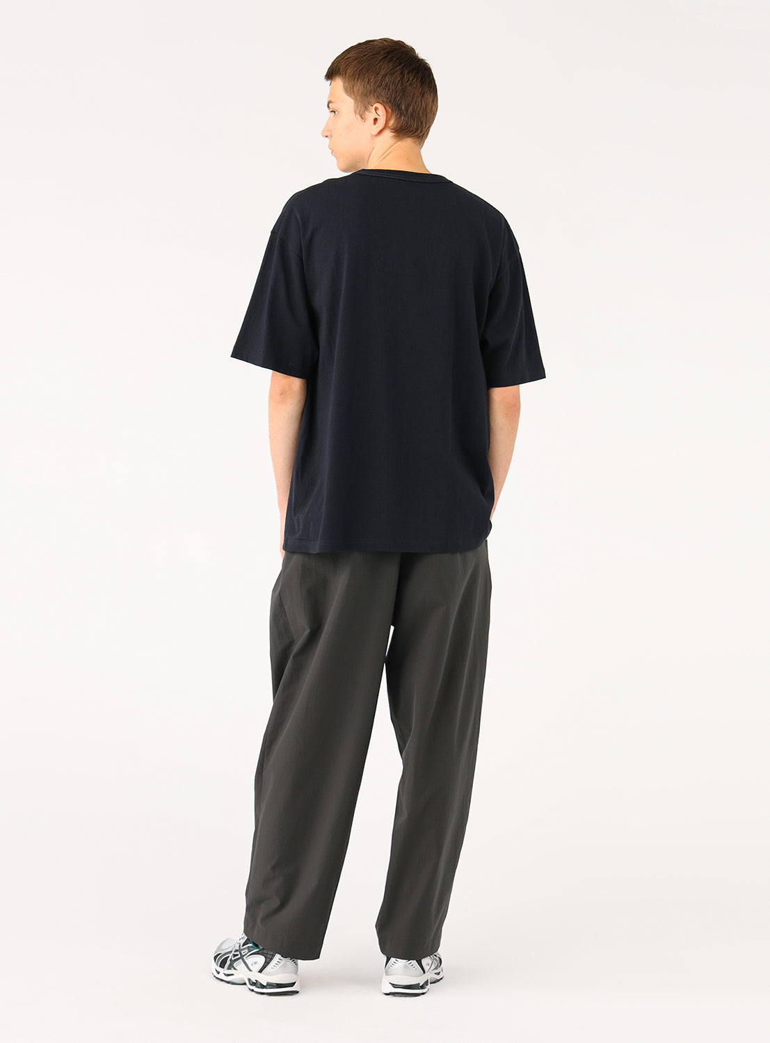 Model wearing a navy plain t-shirt and dark pants, back view, highlighting the shirt's smooth fabric.