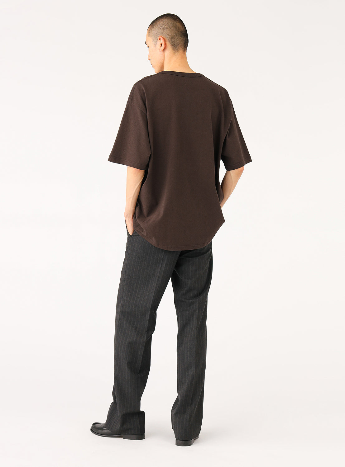 Back view of a man showcasing the fit of a dark brown oversized t-shirt  demonstrating drape.