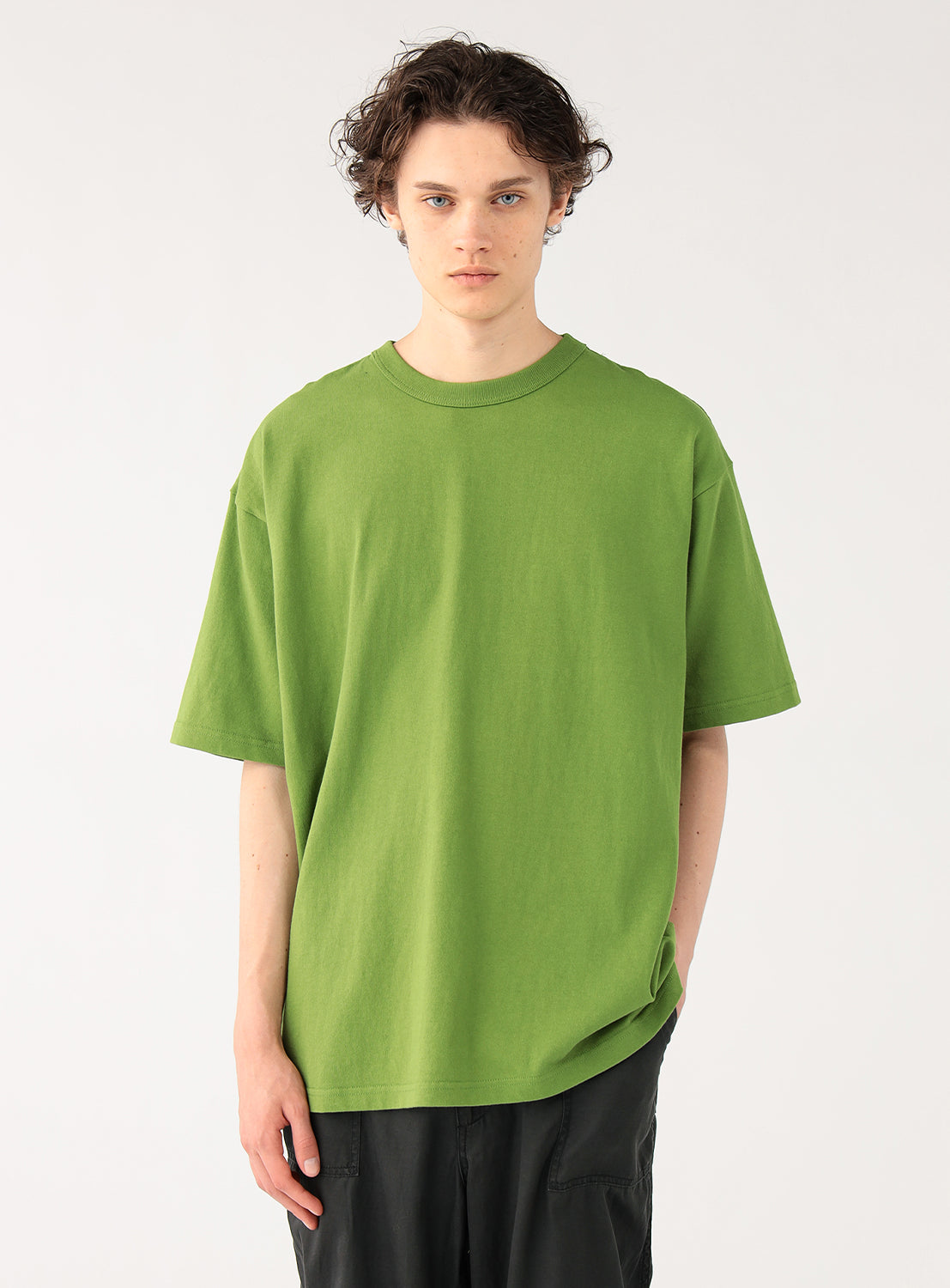 Model wearing a kelly green plain t-shirt and dark pants, front view, displaying its versatile casual style.