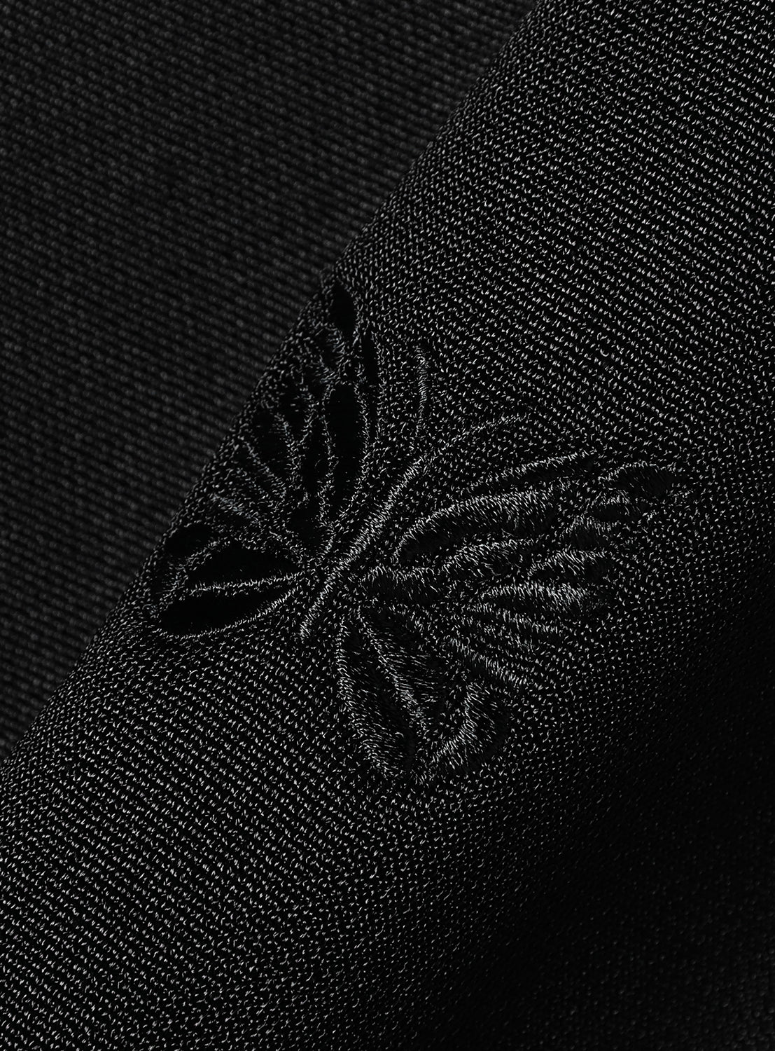 Close-up of a black sweatshirt fabric with an embroidered butterfly. 
