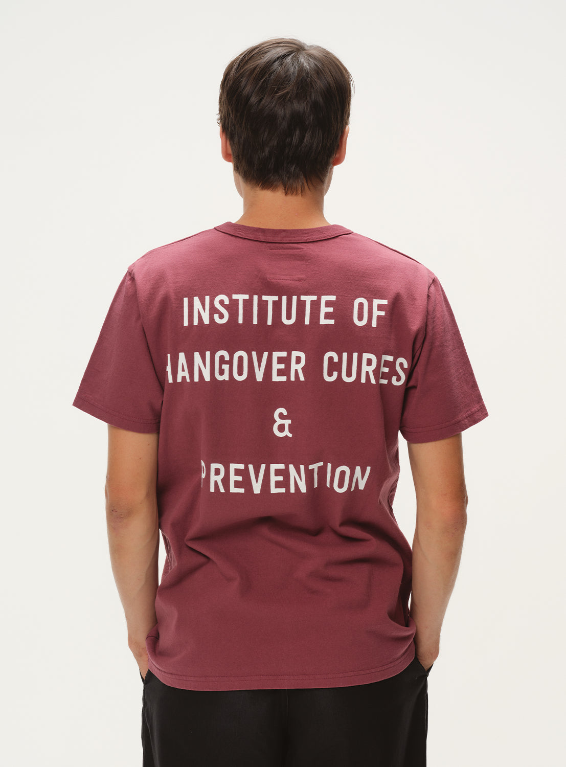 Model wearing maroon t-shirt, back view, showcasing white "INSTITUTE OF HANGOVER CURES & PREVENTION" graphic.