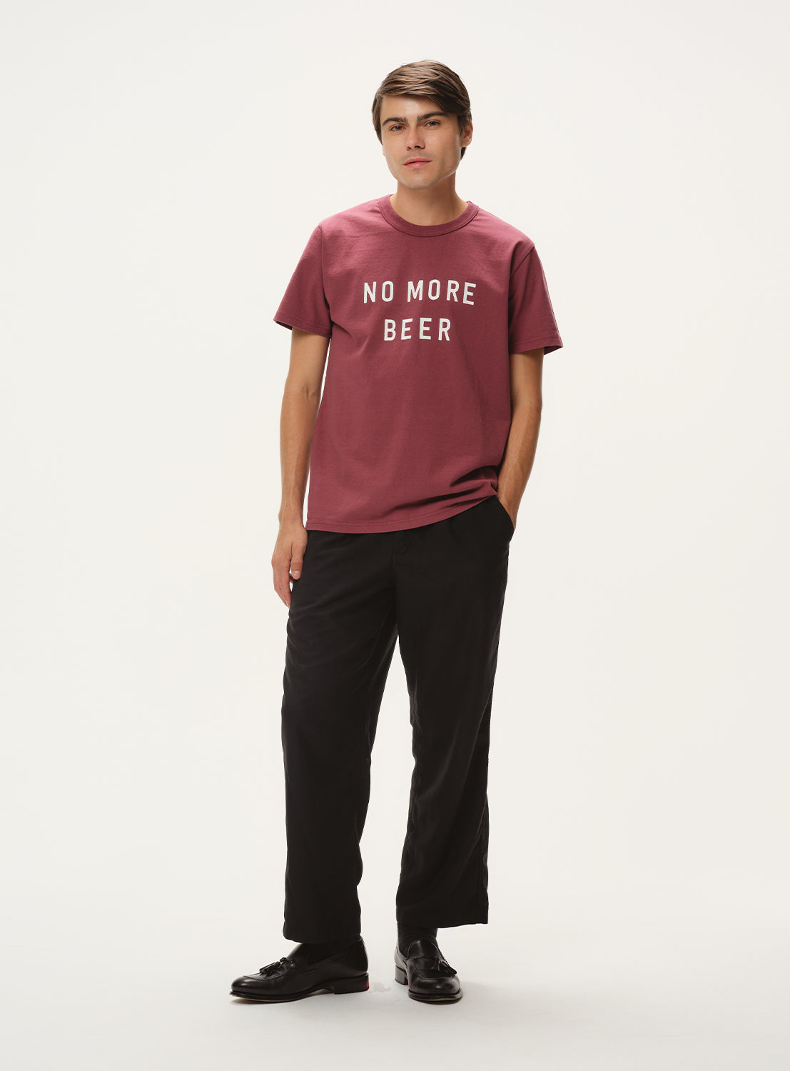 Model wearing maroon t-shirt with "NO MORE BEER" graphic and black pants, full front view, displaying casual outfit.