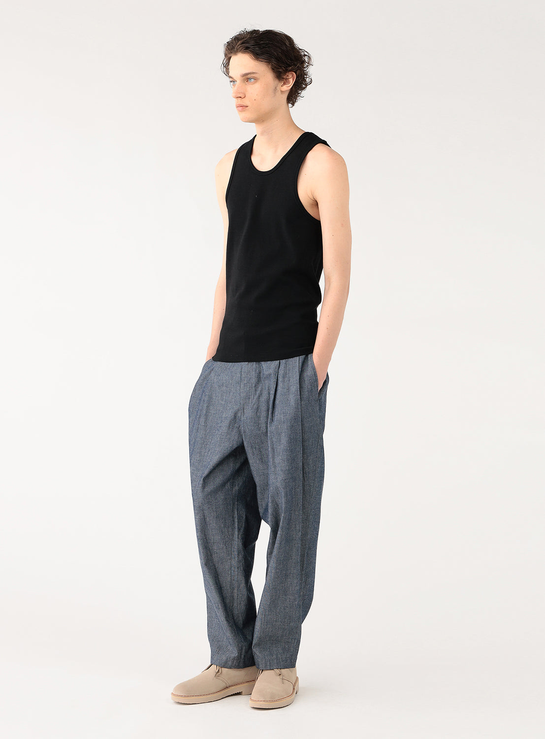 Profile view of a model wearing a black ribbed tank top, showing the garment's cut