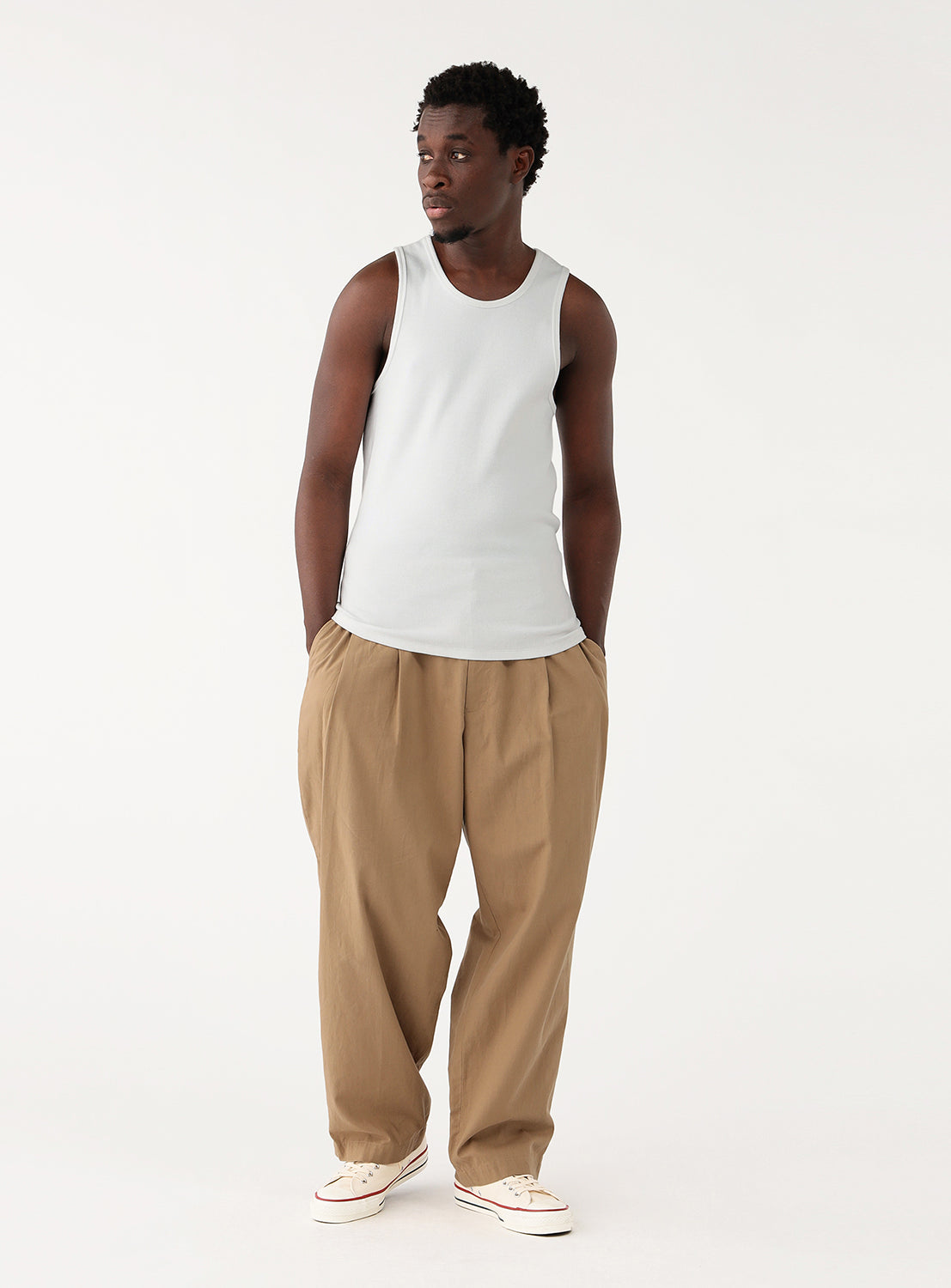Back view of a model in a white ribbed tank top, showcasing the top's fit and the back of the pants.