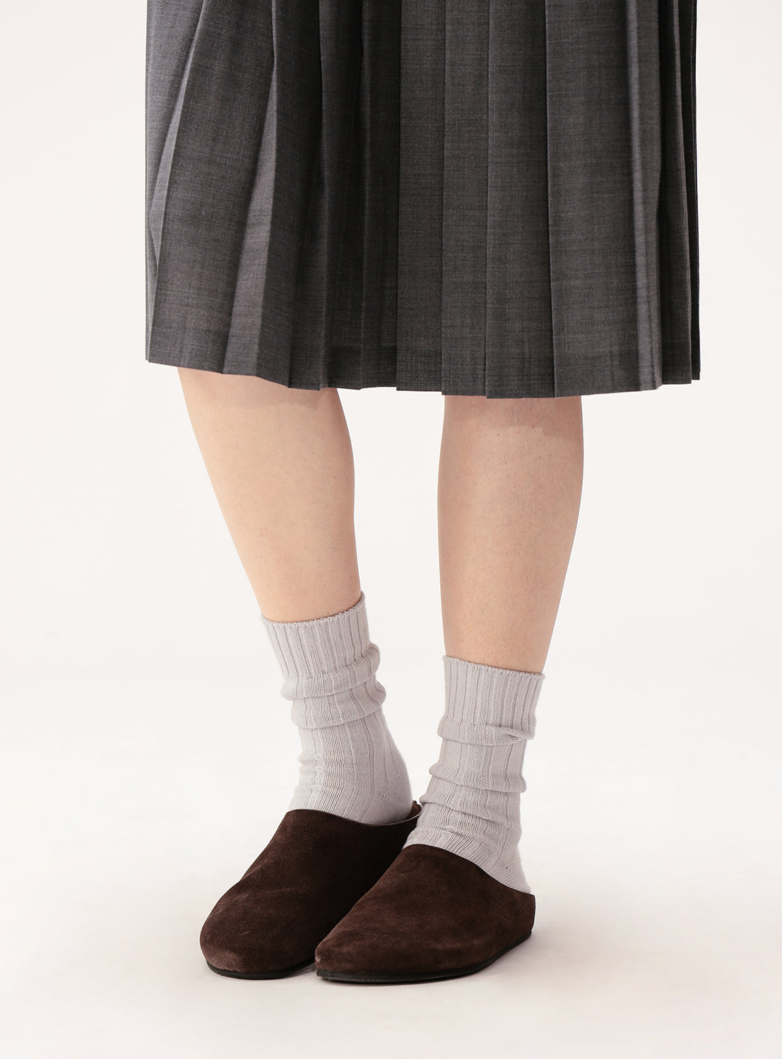 A person is shown from the lower legs down, wearing a gray pleated skirt, BEAMS BOY Cotton Silk Ribbed Socks in light gray, and dark brown slip-on shoes, standing against a light background.