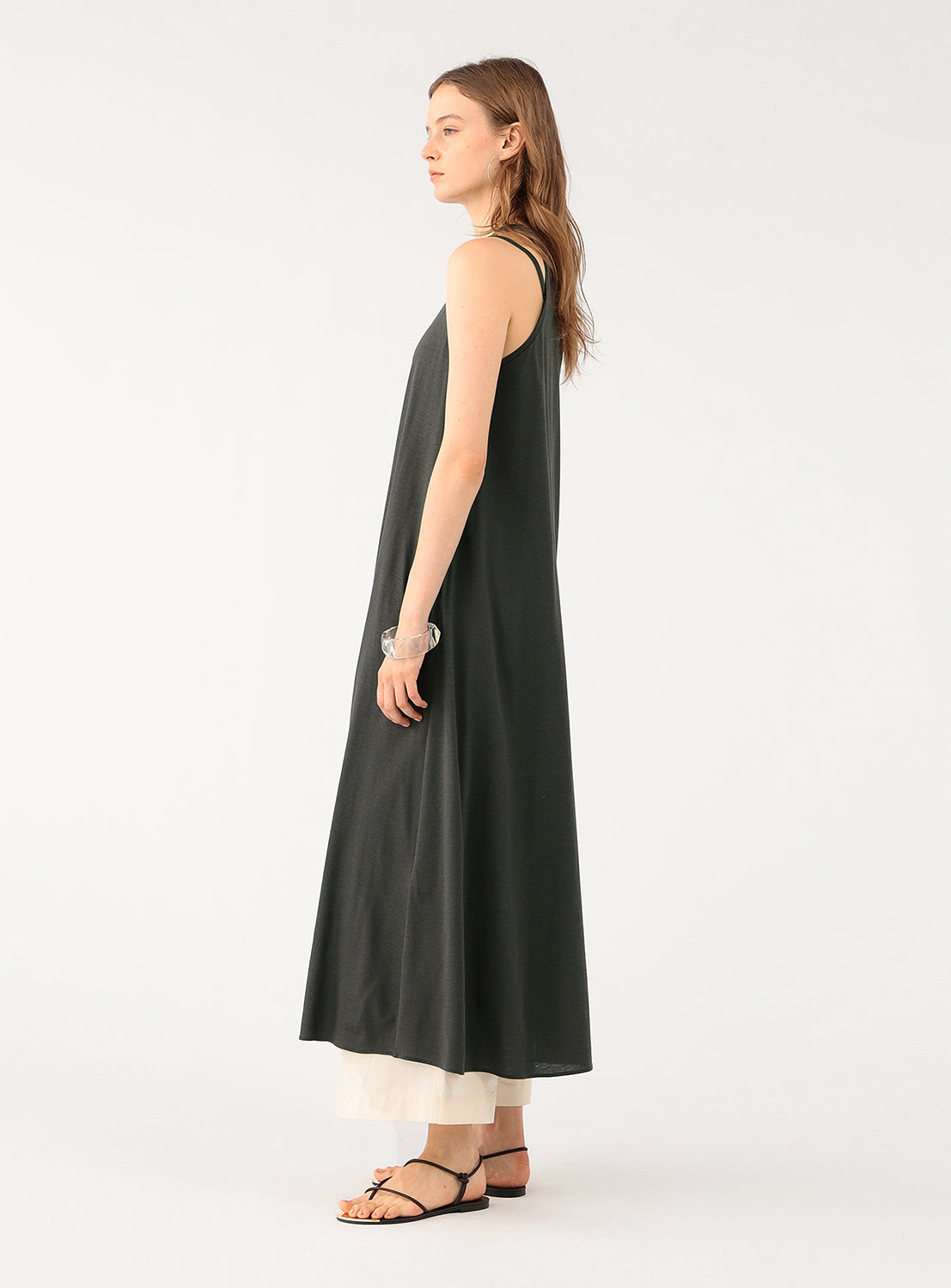 Side view of a model wearing a grey A-line maxi dress, showing the relaxed drape and layered styling.