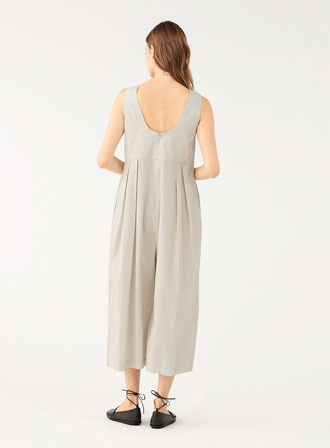 Model wearing a cream 100% cotton wide-leg jumpsuit, back view, highlighting the relaxed fit and back details.