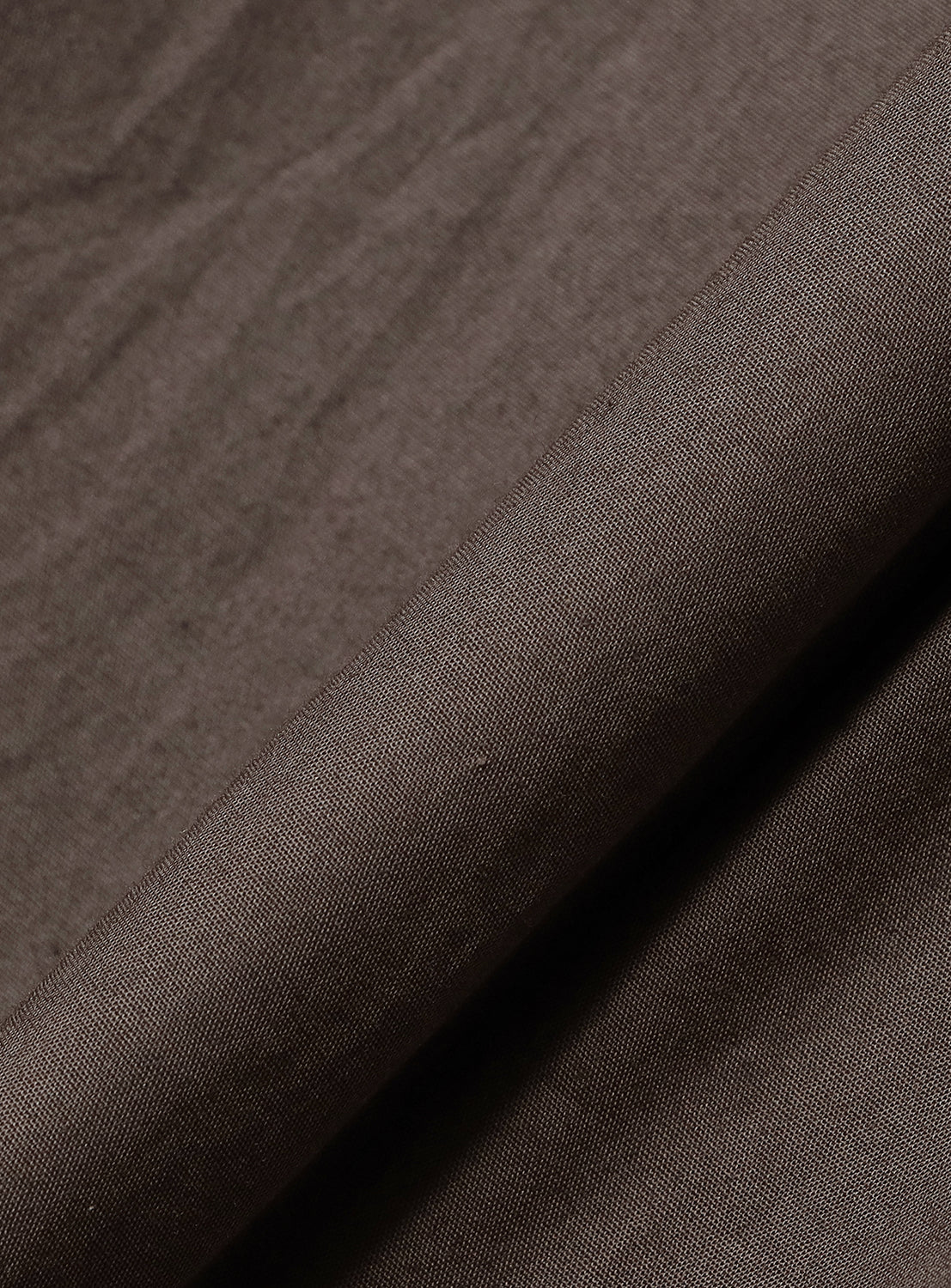 Close-up of the brown material, highlighting the quality and subtle texture of the jumpsuit.