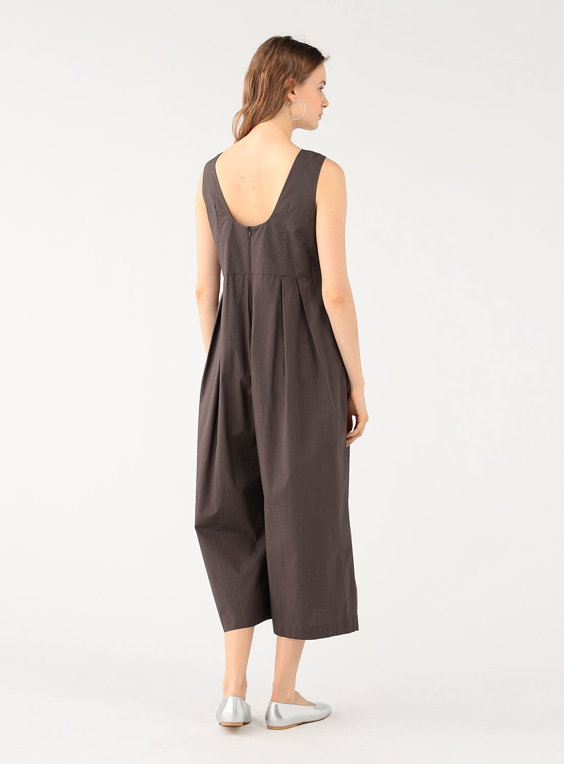 Back view of a model in the brown jumpsuit, highlighting the scoop back and relaxed silhouette.