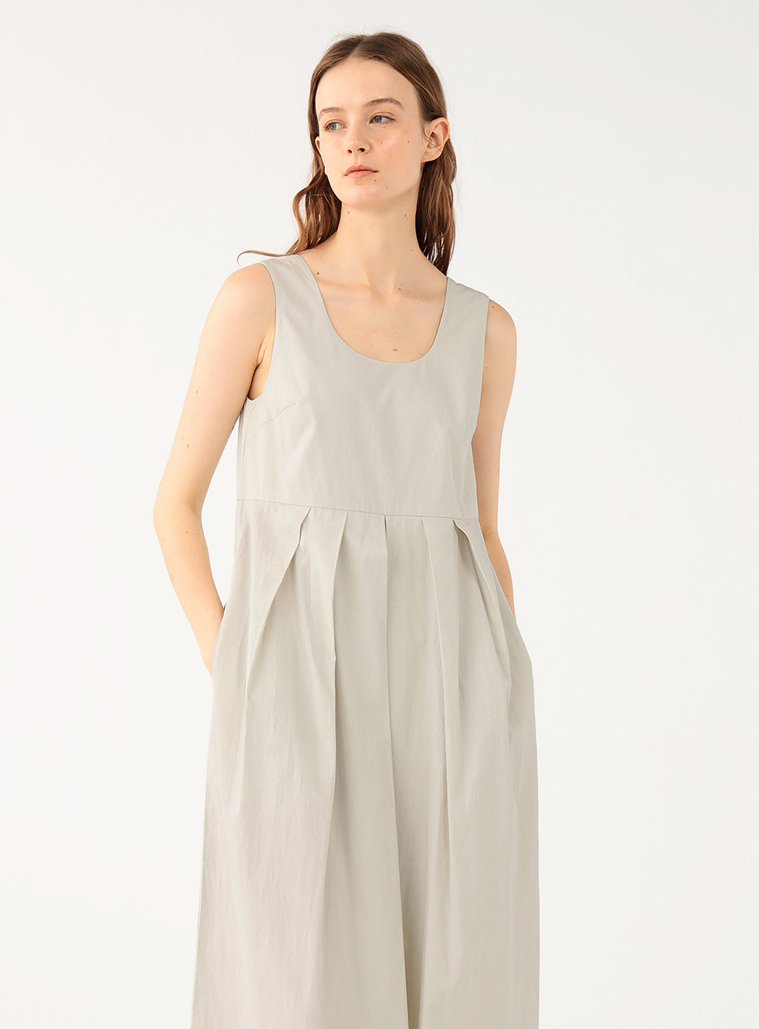 Model wearing a cream 100% cotton wide-leg jumpsuit, front view, displaying the details of the pleats.