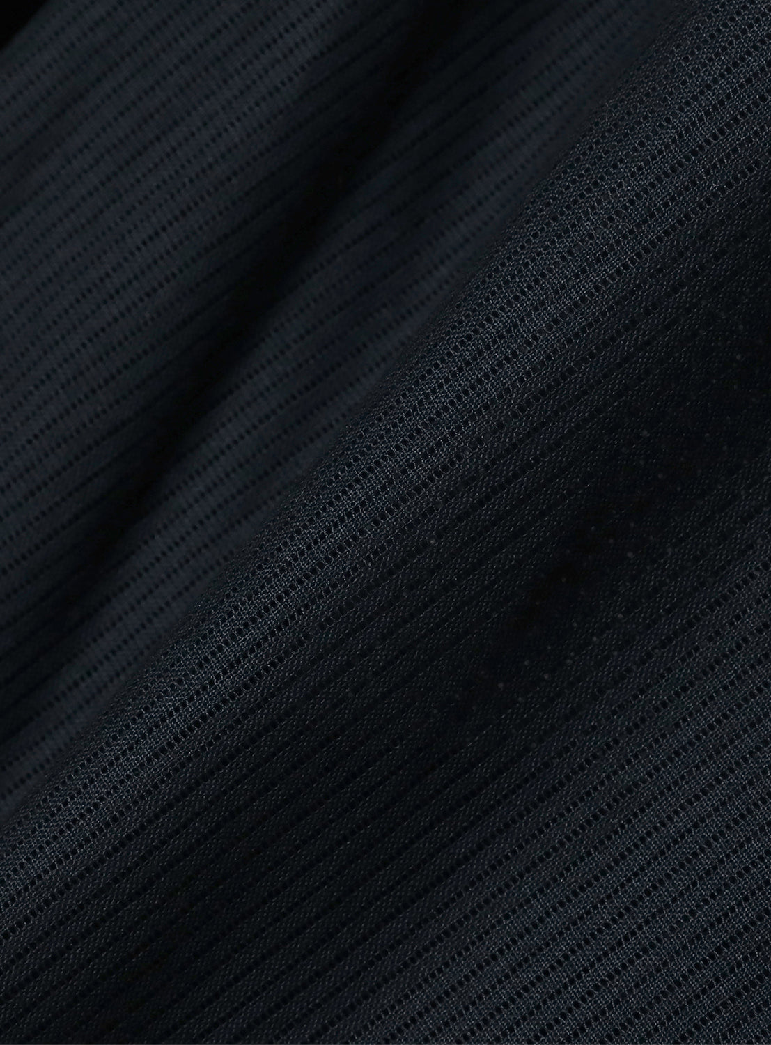 A close-up of dark navy blue, textured fabric, showing the weave of the blazer.