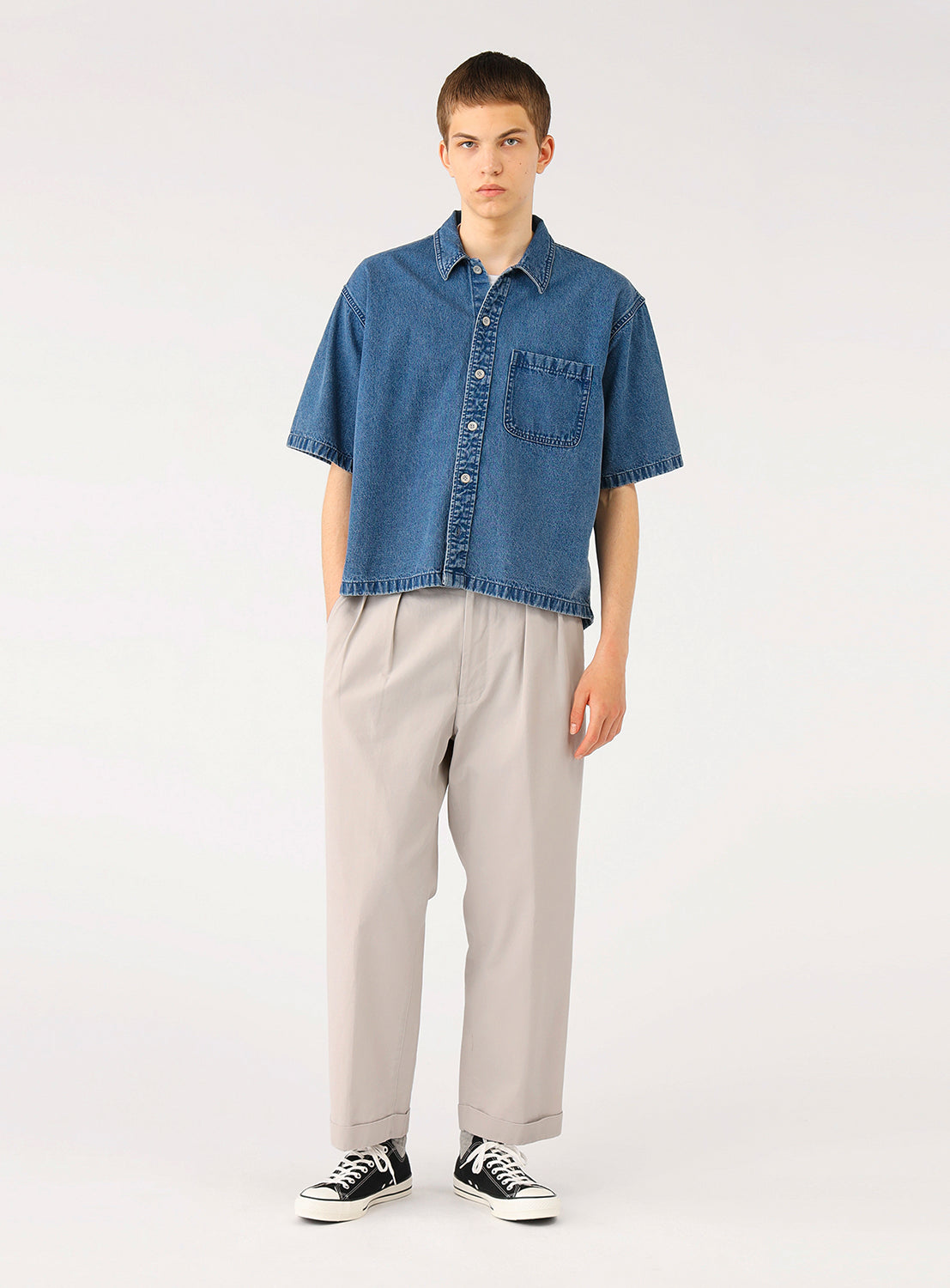 Full front view of model wearing BEAMS Short Denim Shirt in blue indigo denim, featuring a relaxed boxy fit, open camp collar, short sleeves, and oversized chest pockets.