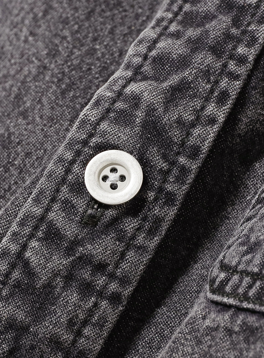 Close-up of black denim fabric on the BEAMS Short Denim Shirt, highlighting the durable weave texture and a contrasting white button with smooth finish and precise stitching.