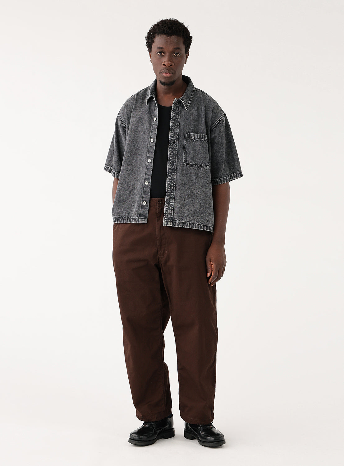Front view of model wearing BEAMS Short Denim Shirt in black denim, featuring a relaxed boxy fit, open camp collar, short sleeves, and oversized chest pockets.