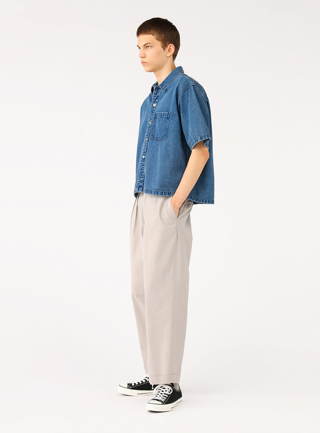 Side view of model wearing BEAMS Short Denim Shirt in blue indigo denim, showcasing the relaxed boxy fit, short sleeves, and structured camp collar.