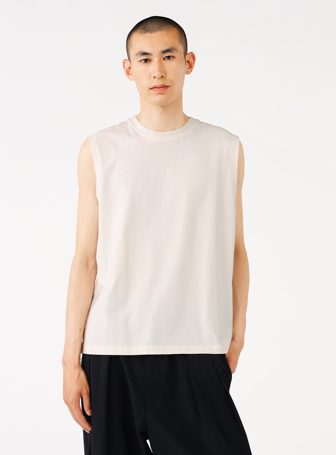 model wearing a white sleeveless top, styled with black pants