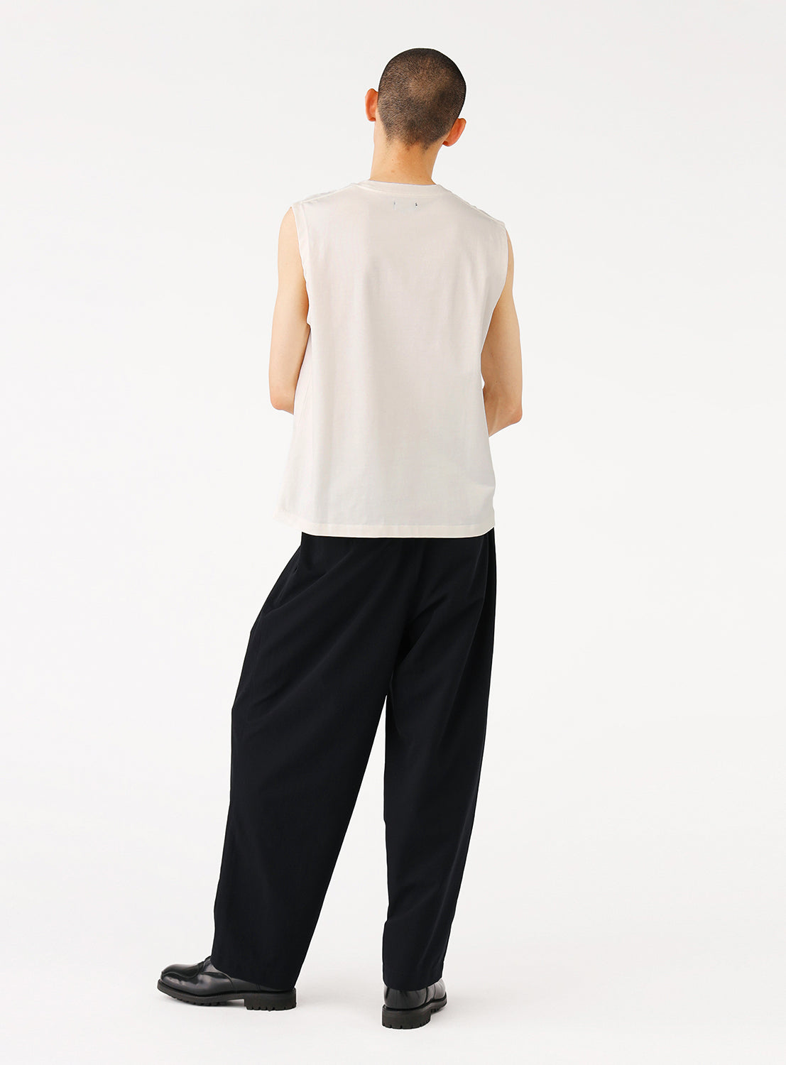 Back view of a model in the white sleeveless top, showing the full design and fit.