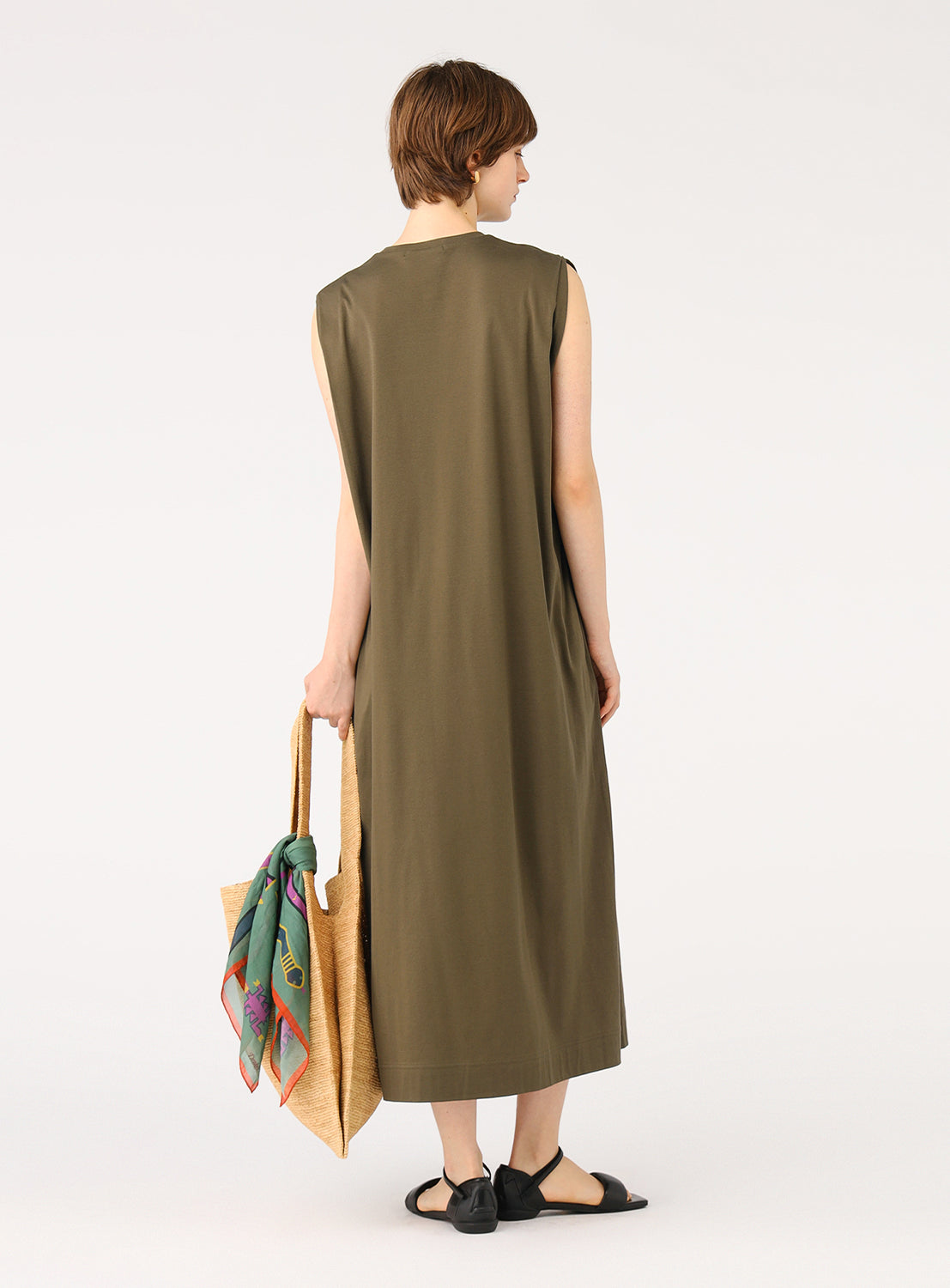 Back view of a model wearing a khaki midi dress, carrying a tote bag.