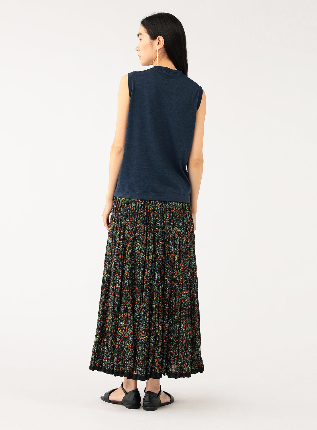 Back view of a model wearing a navy sleeveless top with a floral skirt.