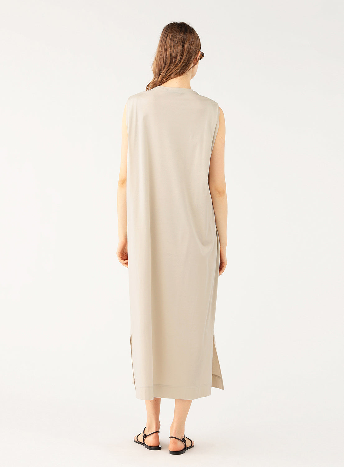 Back view of a model wearing an light grey midi dress, highlighting the simple, clean design and full length.
