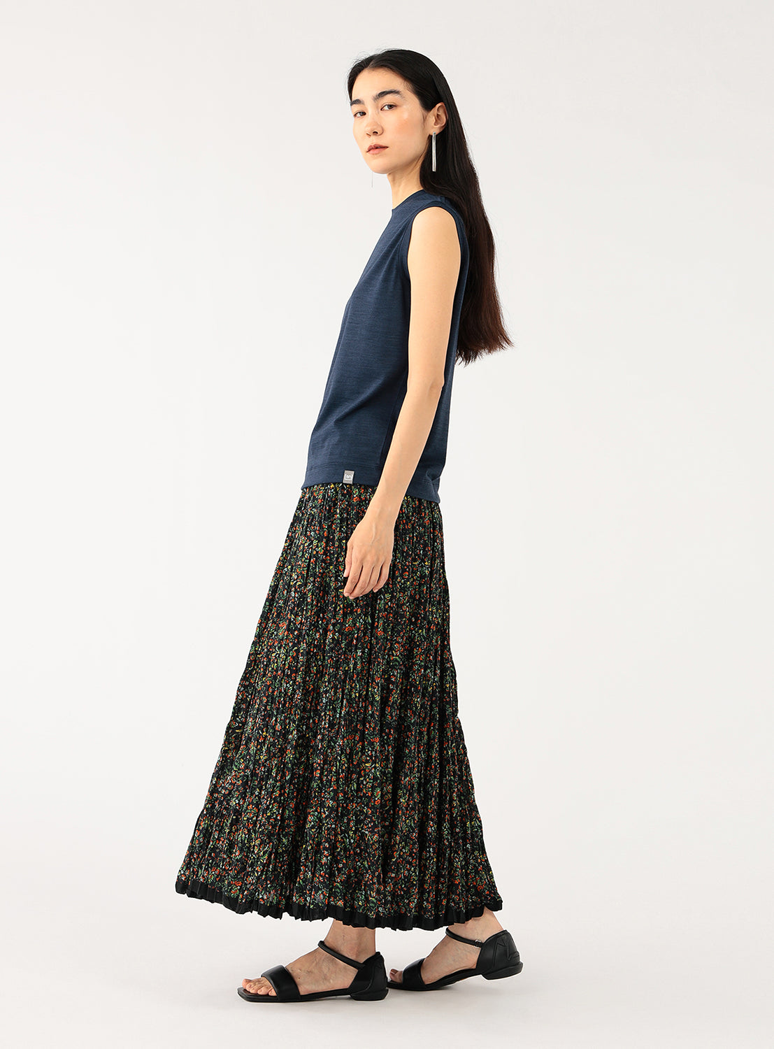 Side view of a model wearing a navy sleeveless top with a floral skirt.