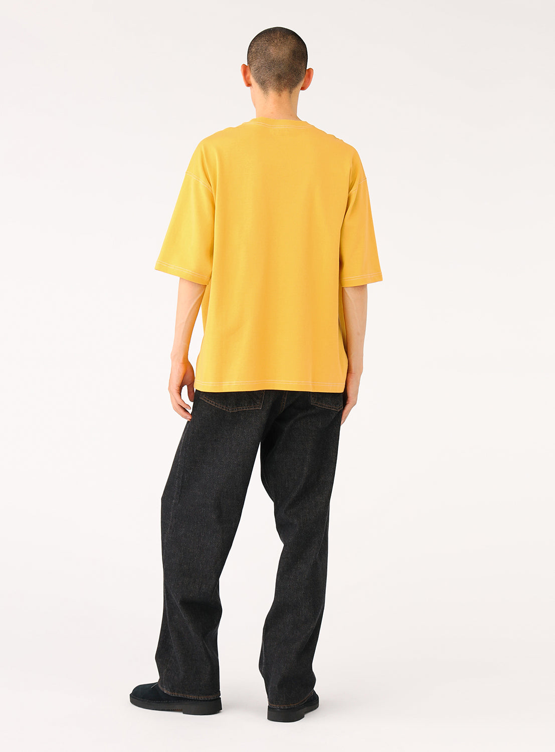 Back view of a model in the yellow t-shirt, showcasing the relaxed fit and contrast stitching on the back.