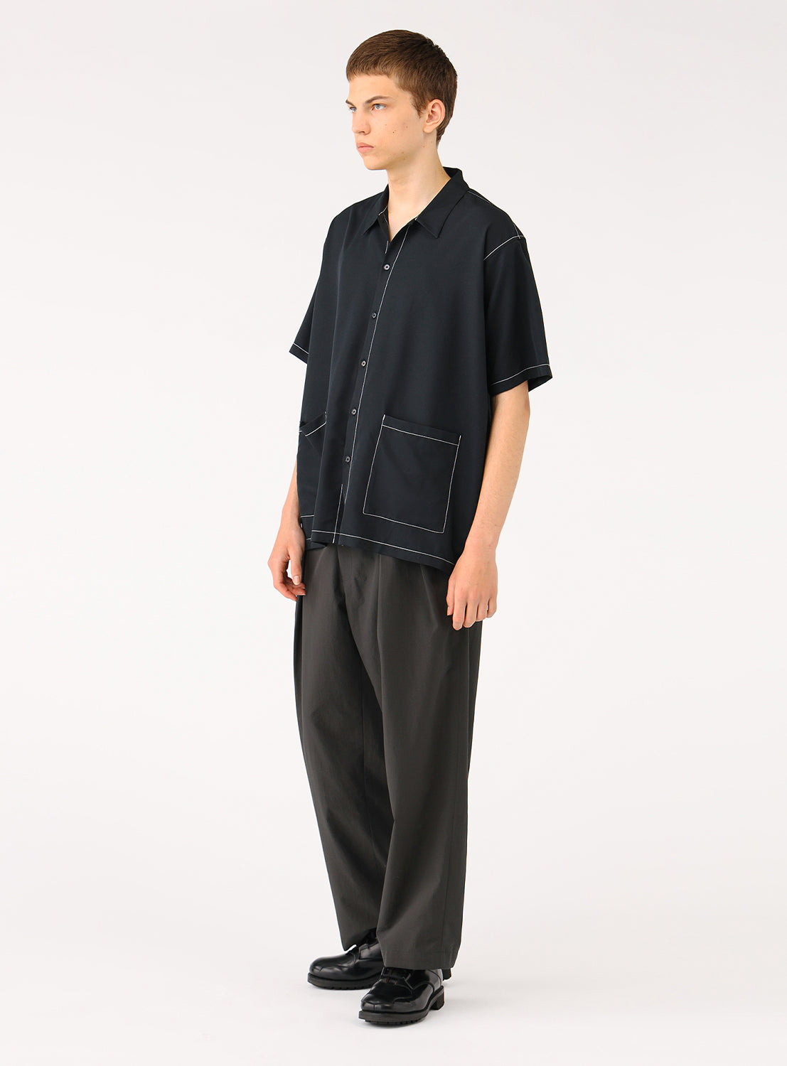 Quarter front view of a model wearing the black BEAMS Stitching Easy Shirt, highlighting the wide, relaxed silhouette and clean lines. 